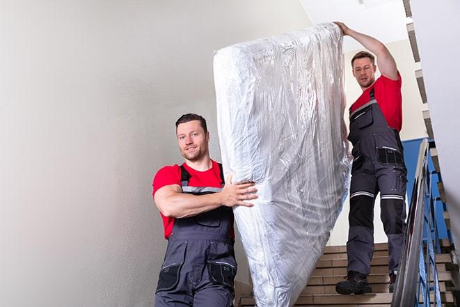 heavy lifting as a box spring is carried out of a house in Oakland