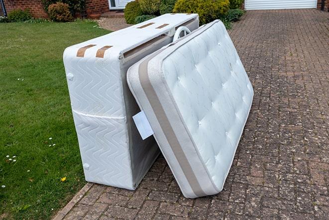 two workers carrying a mattress out of a home